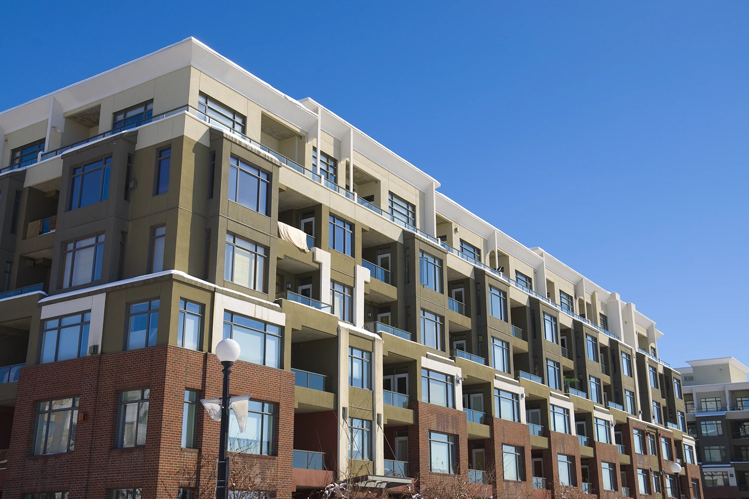 Modern multi-story apartment building with balconies under a clear blue sky.