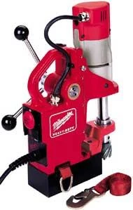 Red Milwaukee magnetic drill press with power cord and a red strap accessory placed beside it.
