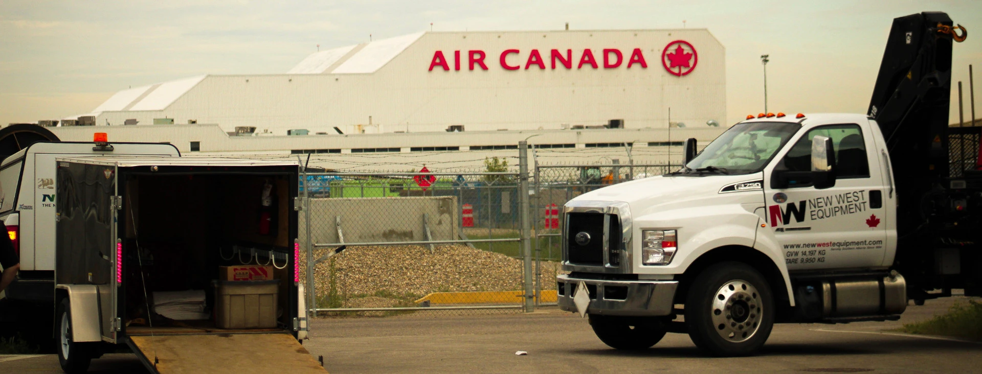 Outdoor airport scene showing an Air Canada airplane in the background with ground support vehicles and equipment in the foreground.